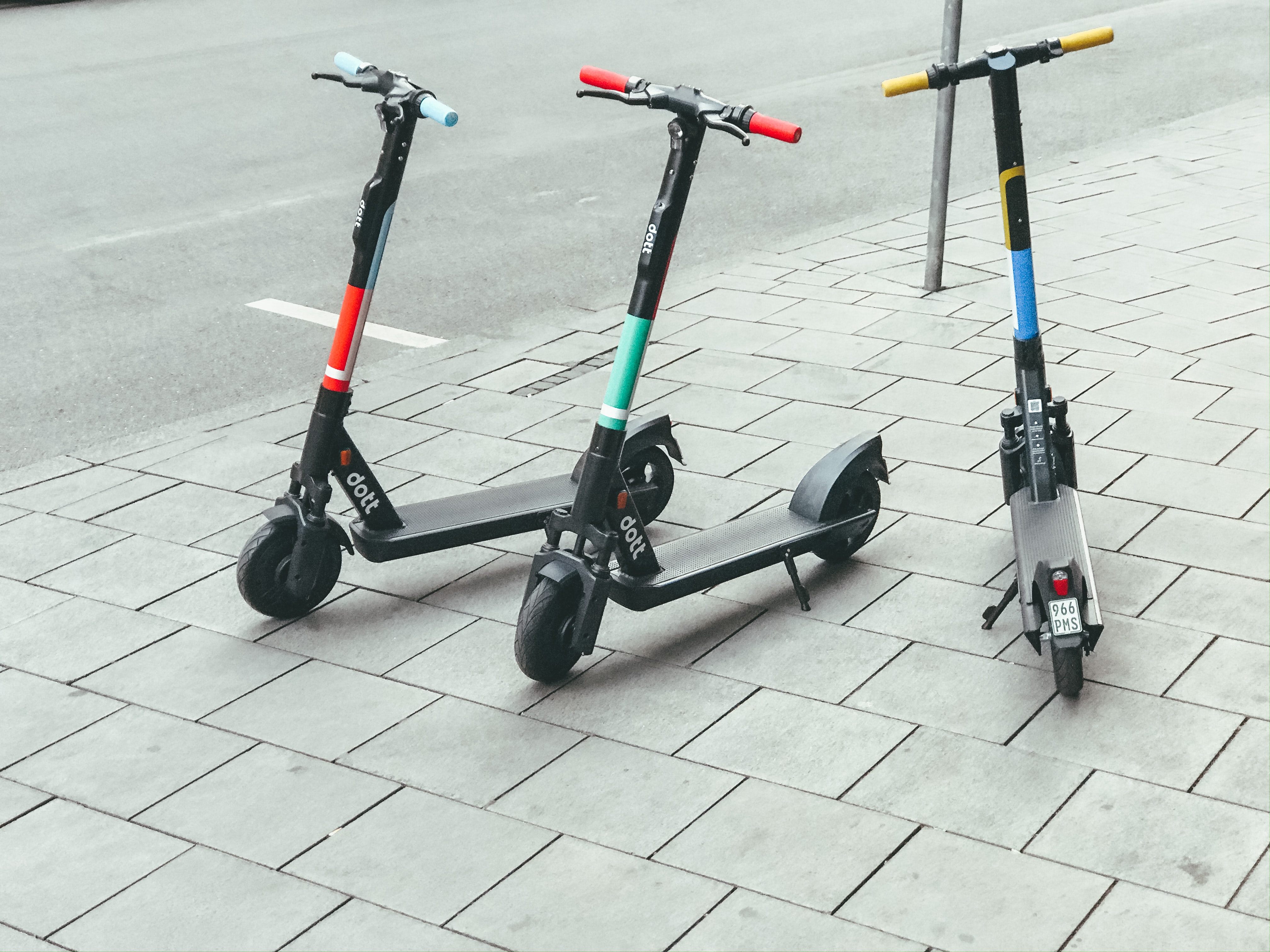 three scooters in a row parked on a sidewalk