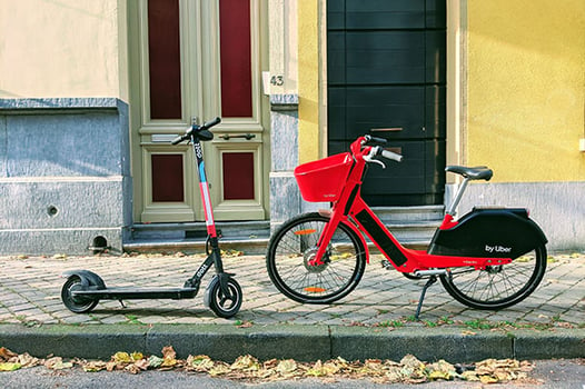 an e-scooter and an e-bike parked on the sidewalk